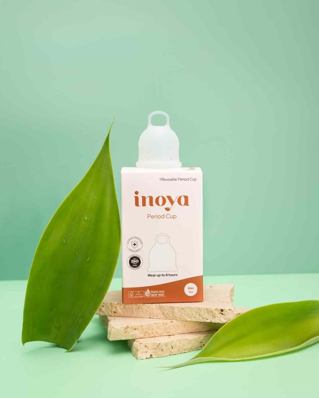 Inova period cup packaging on a green background with leaves
